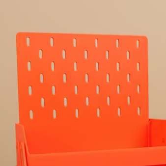 An orange plastic multi-tier desk organizer with a pegboard back panel, shown on a wooden desk with a laptop and other office items in the background.